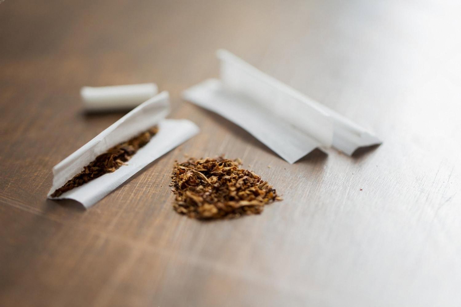 Loose tobacco and rolling papers on a wooden table, showing budget nicotine choices